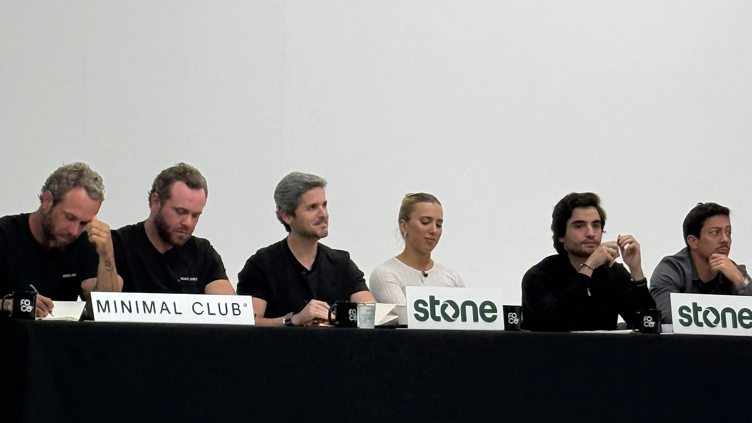 A bancada de Os Caras do Pix à mesa preta, com as placas da Minimal Club e da Stone.